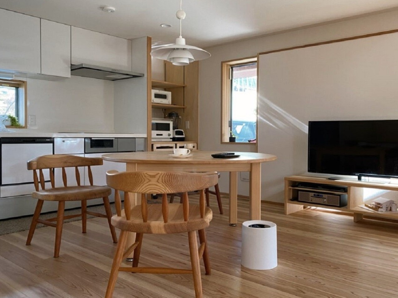 白い壁・天井に対し、床とテーブル・椅子を無垢で揃え、見た目の重心を下げている