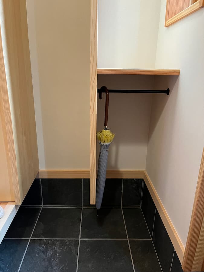 玄関は雨の日の動線もスムーズな傘掛けとレインコート用のハンガーパイプを設けた